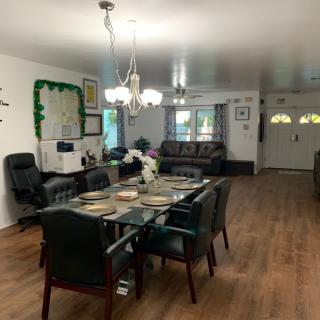 A spacious dining and living area with a table set for dinner, featuring a chandelier and wooden flooring.