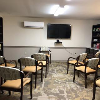 A small meeting room with chairs arranged in rows facing a television screen.