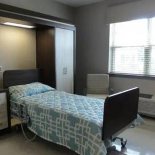 A hospital room with a bed and a window.