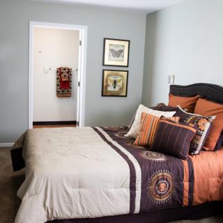 A cozy bedroom with colorful bedding and wall art.