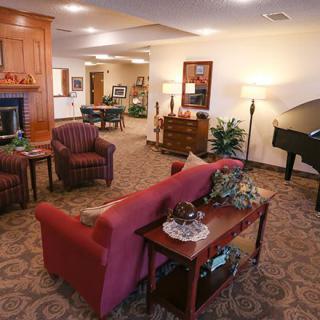 A cozy living room with a red sofa, piano, and elegant decor.