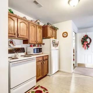 A cozy kitchen with wooden cabinets and modern appliances, featuring a microwave, stove, and refrigerator. Seasonal decorations add charm to the space.