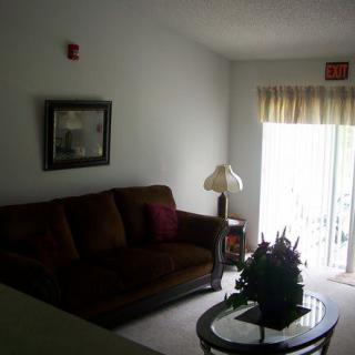 A cozy living room with a sofa, lamp, and coffee table near sliding glass doors.