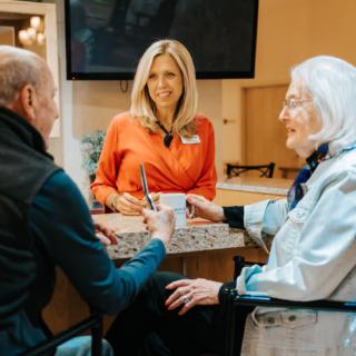 A caregiver interacting with elderly individuals at a care facility.