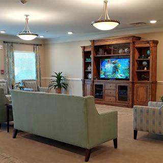 A cozy living room with a large sofa facing a television, surrounded by bookshelves and soft lighting.