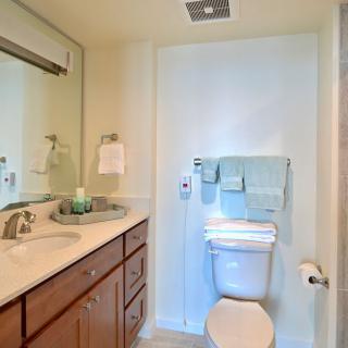 A neatly organized bathroom with a sink, mirror, and toilet.