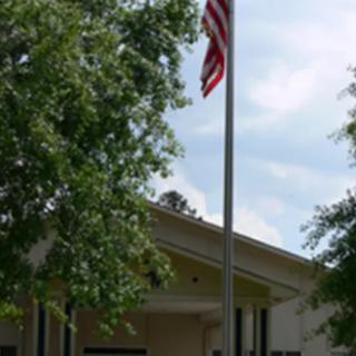 A building with an American flag flying outside, surrounded by trees.