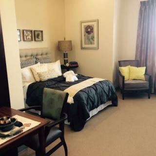 A cozy bedroom with a neatly made bed, armchair, and stylish decor.