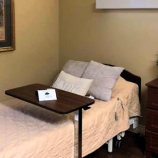 A hospital bed with pillows and an adjustable table in a room.