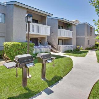 An outdoor view of an apartment complex with balconies and grilling stations along a landscaped pathway.