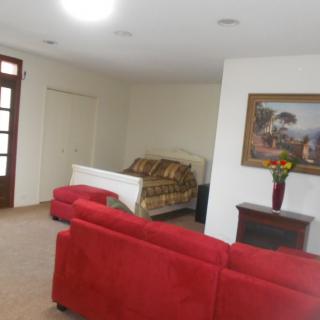 A spacious living area featuring a red sofa, a bed, and decorative painting on the wall.