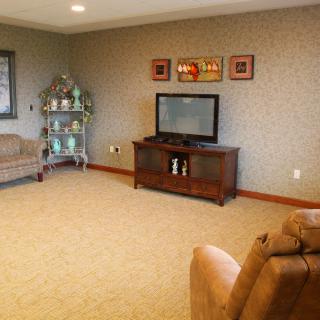 A cozy living room with a television, sofa, and decorative shelf.