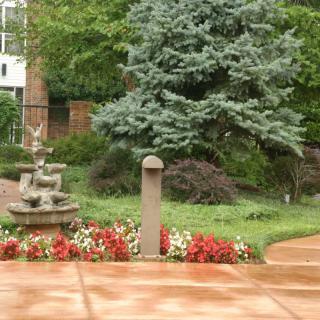 A serene garden scene with a fountain, colorful flowers, and lush greenery.