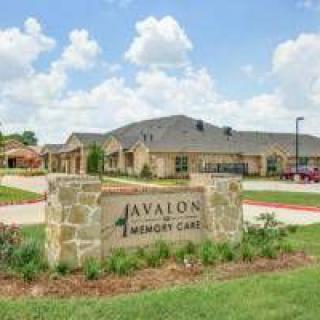 Avalon Memory Care facility with a stone sign and surrounding greenery, set under a partly cloudy sky.