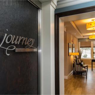 A warmly lit hallway leading into a cozy interior space, marked with the word 'journey' on the door.