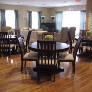 A well-furnished dining area with round tables and chairs on a wooden floor.