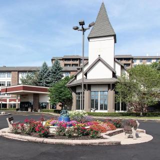A hotel building with a landscaped entrance featuring colorful flowers and a unique architectural design.