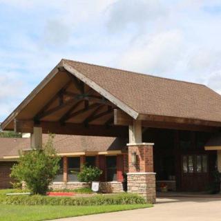 A brick building with a large covered entrance and landscaped surroundings.