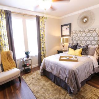 A cozy and stylishly decorated bedroom with a patterned headboard, plush bedding, and accent pillows.