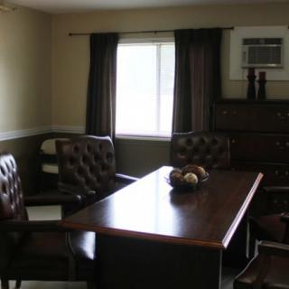 A small office meeting room with a conference table, chairs, and an air conditioning unit.