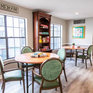 A cozy community room with tables and chairs, perfect for board games or reading by the windows.