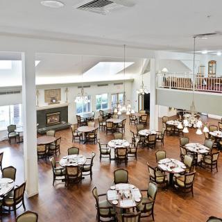 A spacious dining area with neatly arranged tables and chairs, featuring elegant decor and wooden flooring.