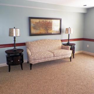 A cozy living room featuring a floral sofa, elegant lamps, and tasteful wall art.