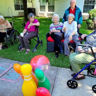 A group of senior citizens enjoying a sunny outdoor game with colorful bowling pins.