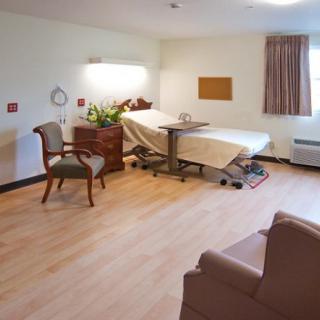 A hospital room featuring a patient bed and seating area.