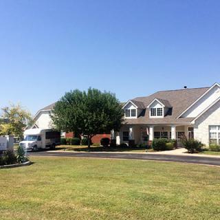 A suburban house with a large lawn and clear blue sky.