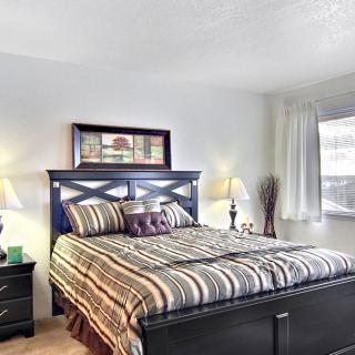 A cozy bedroom with a striped bedspread, wooden headboard, and two lamps.