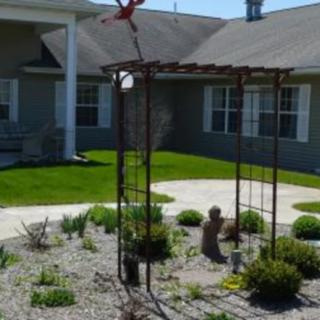 A beautifully landscaped garden with a sculpture in front of a house.
