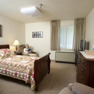 A cozy bedroom with a wooden bed, floral bedding, and matching furniture.