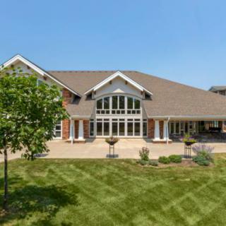 A large suburban house with a well-maintained lawn under a clear blue sky.