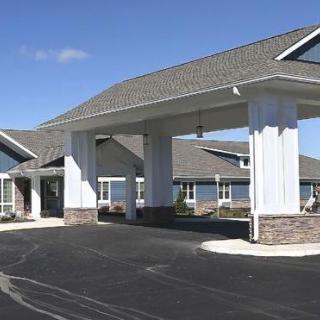 A modern building with a covered entrance and a paved driveway.