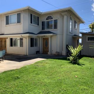 A two-story house with a well-maintained lawn and garden on a sunny day.