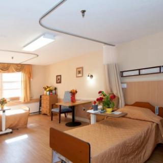A clean and well-organized hospital room with beds and flowers.