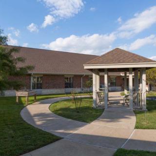 A scenic view of a building with a gazebo and winding pathway under a blue sky.
