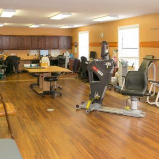 A spacious gym with various exercise equipment and a wooden floor.