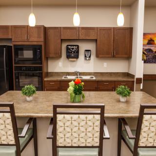 A modern kitchen with wooden cabinets, a central island, and pendant lighting.