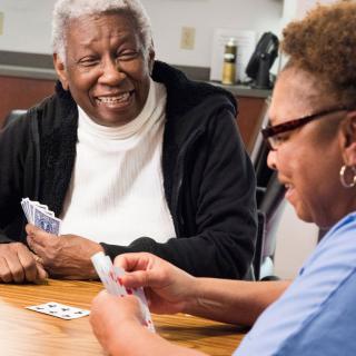 Two seniors enjoying a card game together indoors, smiling and interacting.
