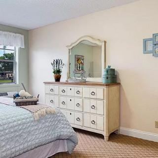 A cozy bedroom featuring a dresser with a mirror, bed, and window allowing natural light.