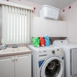 A tidy laundry room featuring a washing machine, dryer, and cleaning supplies.