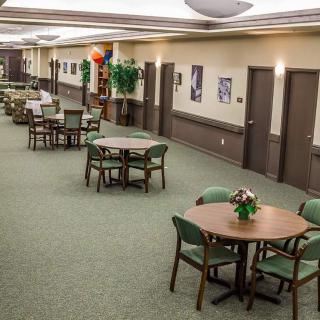 A spacious dining area with neatly arranged tables and chairs, decorated with plants and wall art.