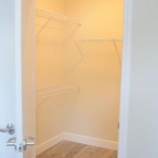 An empty walk-in closet with shelves and hanging rods.