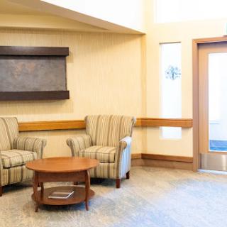 A cozy waiting area featuring two striped chairs and a wooden table, inviting relaxation.