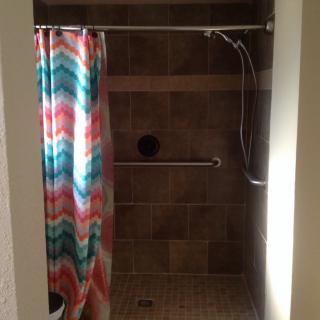 A bathroom shower area with a colorful zigzag-patterned curtain and tiled walls.