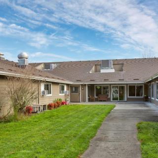 A residential house with a well-maintained lawn under a cloudy sky.