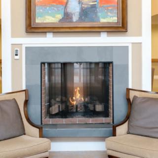 A cozy living room setting with a fireplace surrounded by comfortable seating and artwork hanging above.