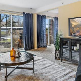 A cozy living room with large windows, blue curtains, and modern furniture.